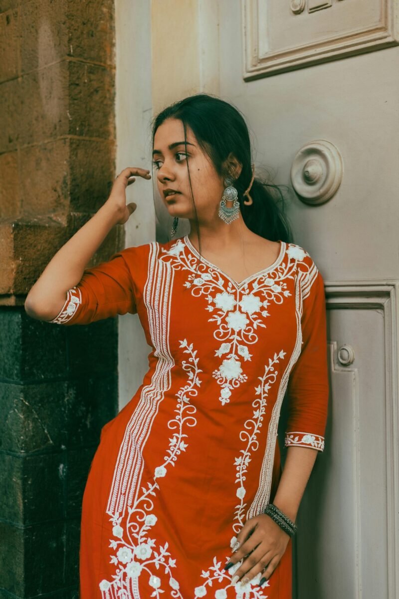 Authentic portrait of a woman in a red kurti on a Mumbai street, showcasing traditional Indian fashion.